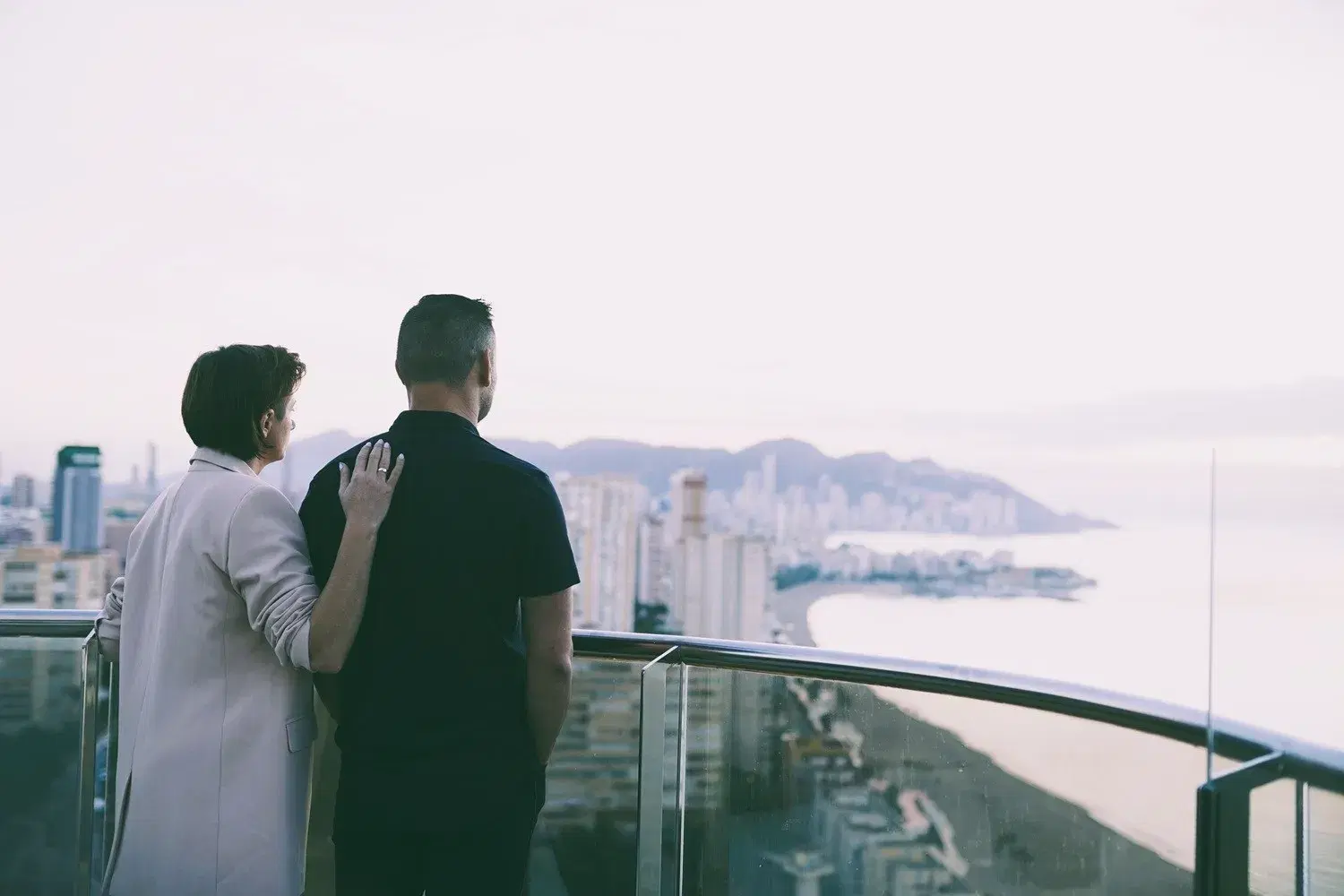 Para kobieta i mężczyzna na balkonie z widokiem na miasto i morze w Hiszpanii. Wyjazd dla par - odnówcie bliskość