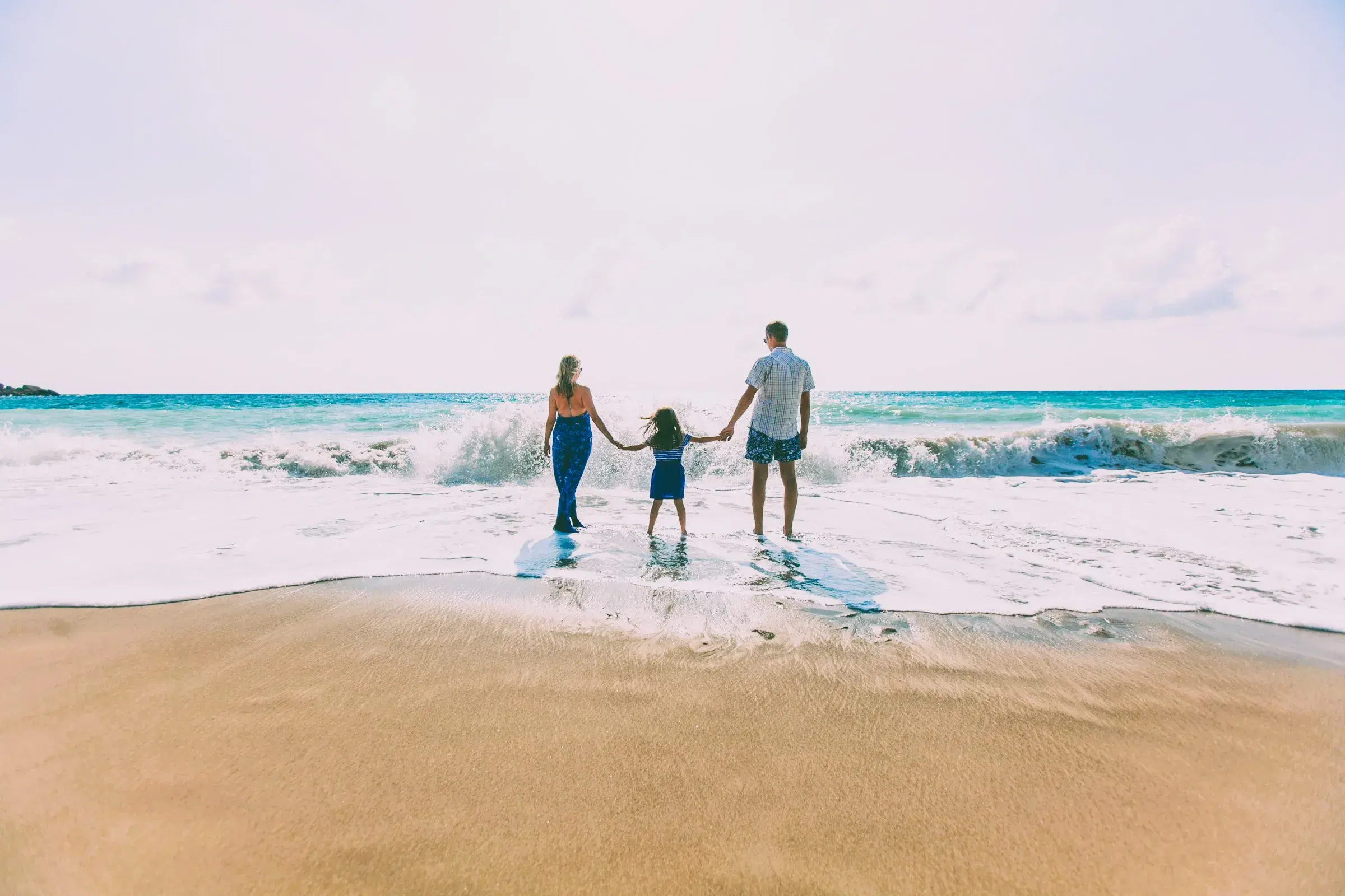 Rodzina kobieta, mężczyzna i dziecko na plaży w Hiszpanii z morzem w tle. Wyjazd dla rodzin - wspólna radość
